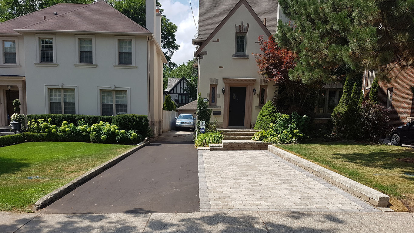Landscaping Toronto - A driveway leading to a house with a car parked next to it.