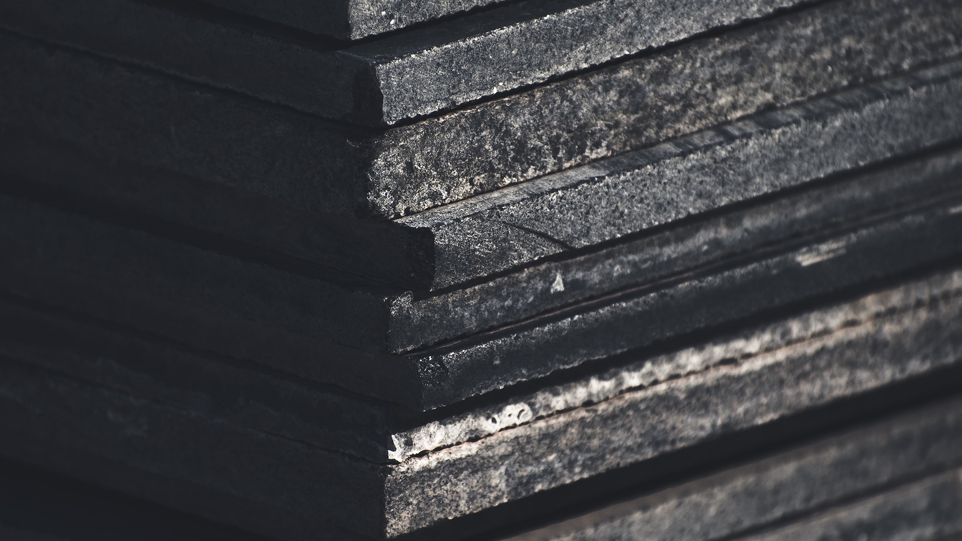Landscaping Toronto - Close-up of a stack of weathered black slate stone tiles showing textures and edges.